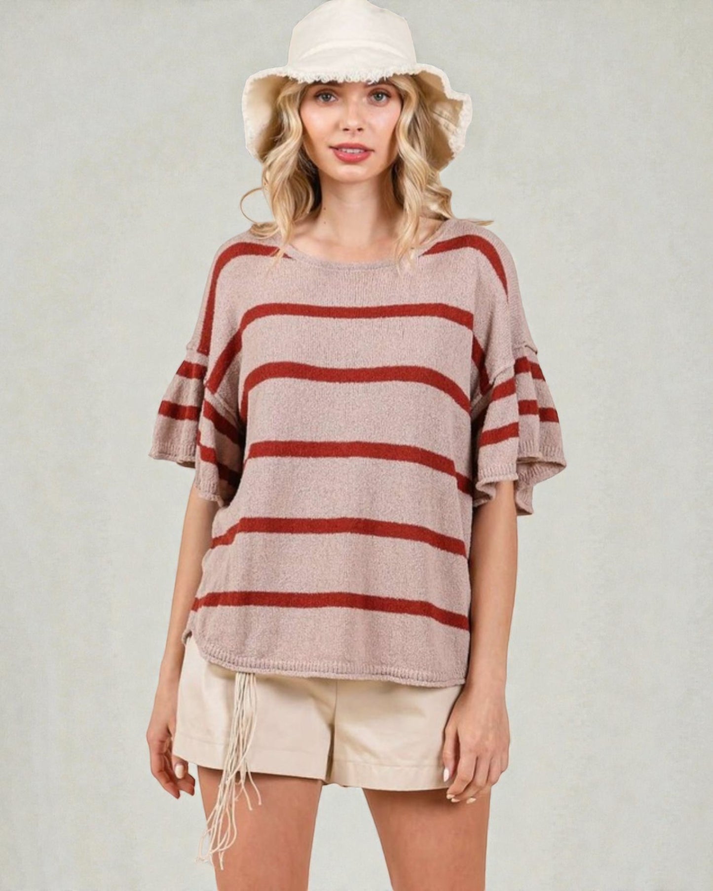 Woman wearing a striped sweater and white shorts with a plain background