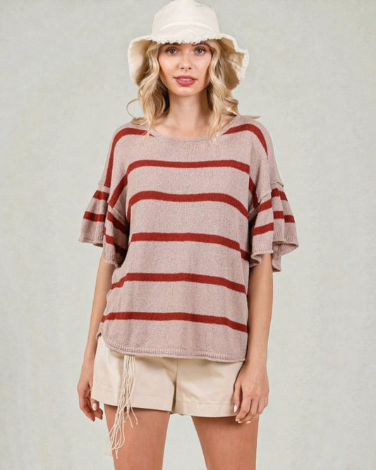 Woman wearing a striped sweater and white shorts with a plain background