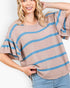 A woman wearing a beige knit top with horizontal blue stripes and flared short sleeves, paired with light blue jeans, against a plain white background.