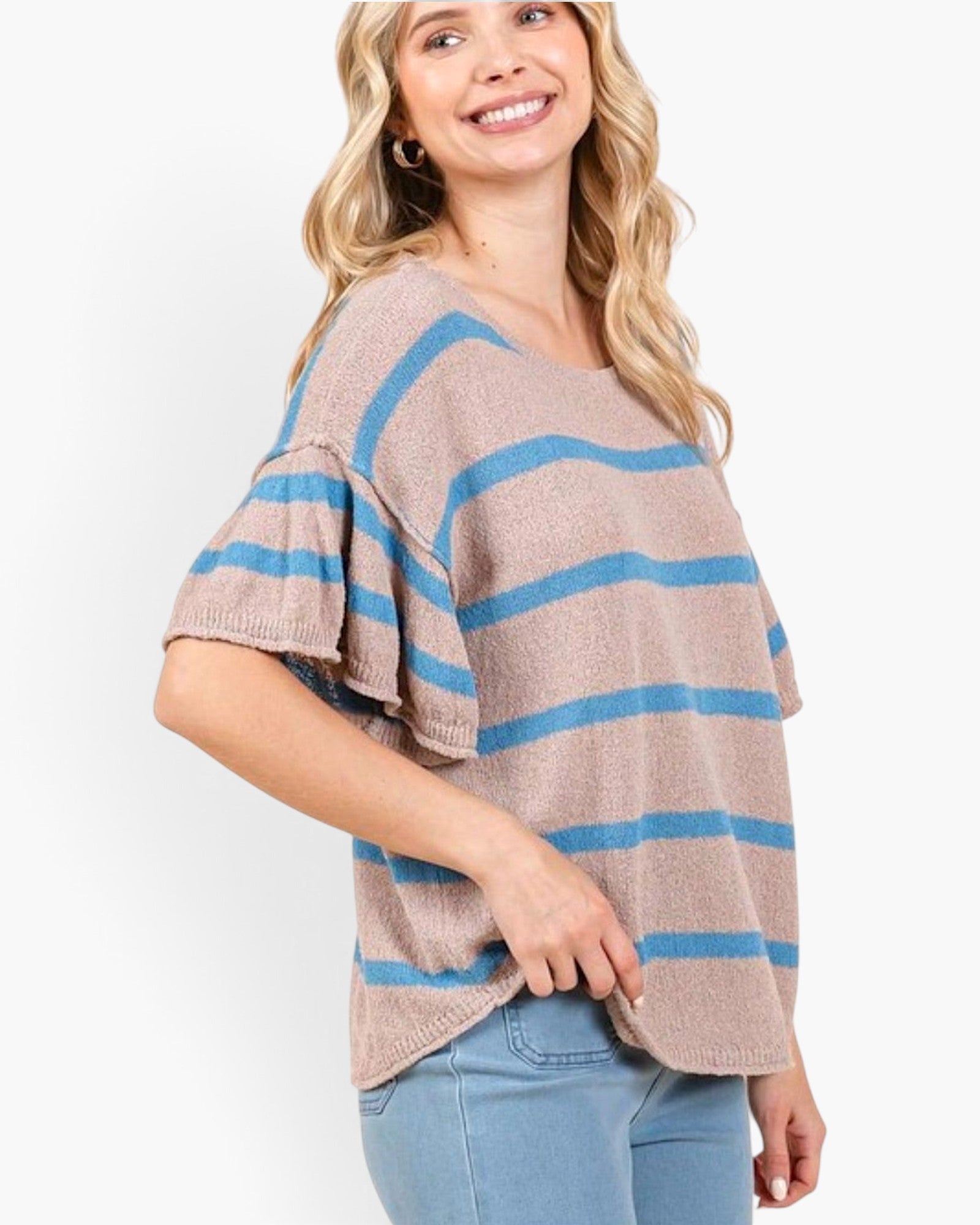 A woman wearing a beige knit top with horizontal blue stripes and flared short sleeves, paired with light blue jeans, against a plain white background.