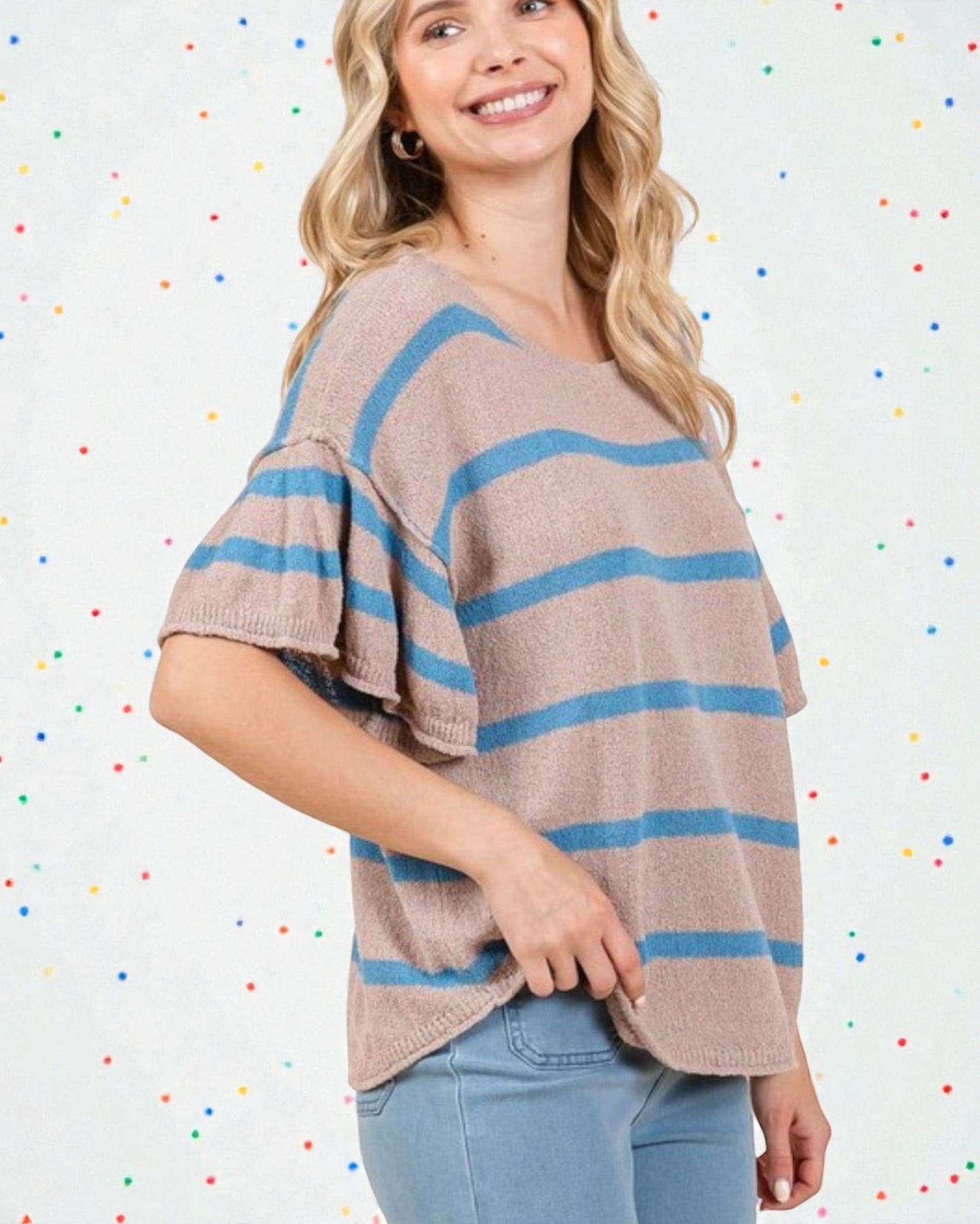 Woman wearing a beige and blue striped sweater against a multicolored polka dot background