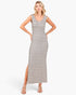 A woman modeling a sleeveless, bodycon maxi dress with horizontal beige and black stripes, standing against a plain white studio background.