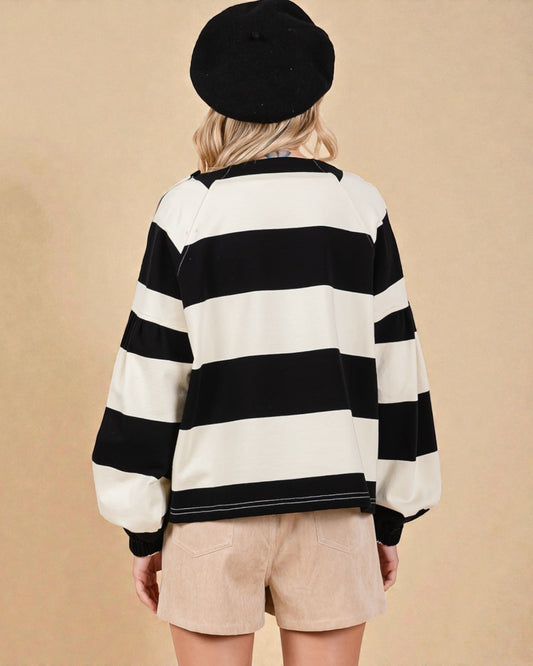 Person wearing a black and white striped sweater with a beige background