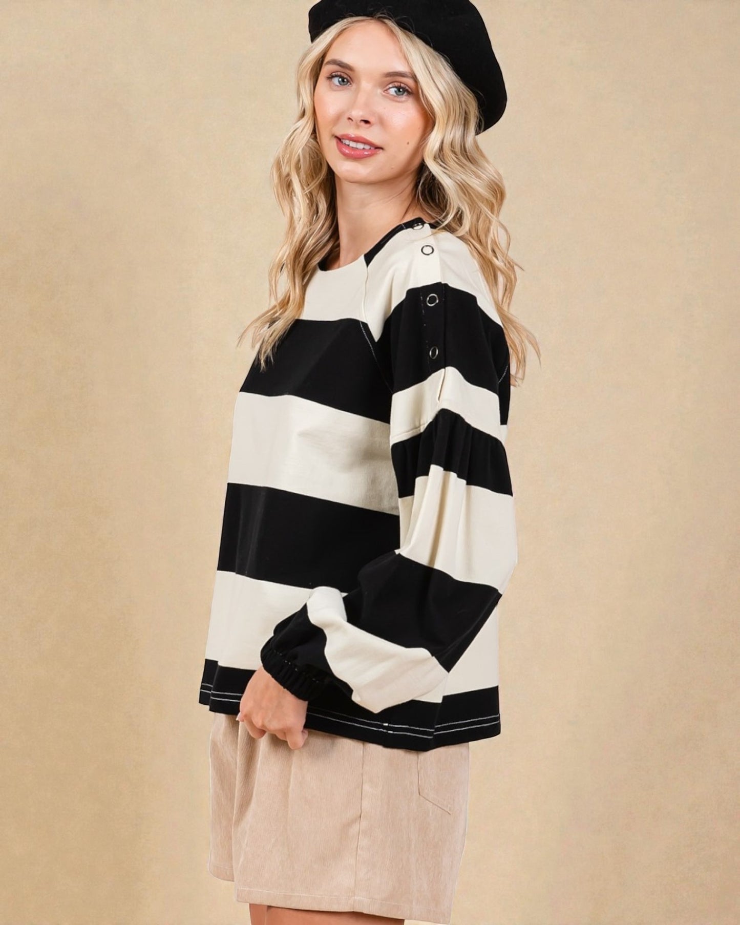 Woman wearing a black and white striped sweater with a beige background