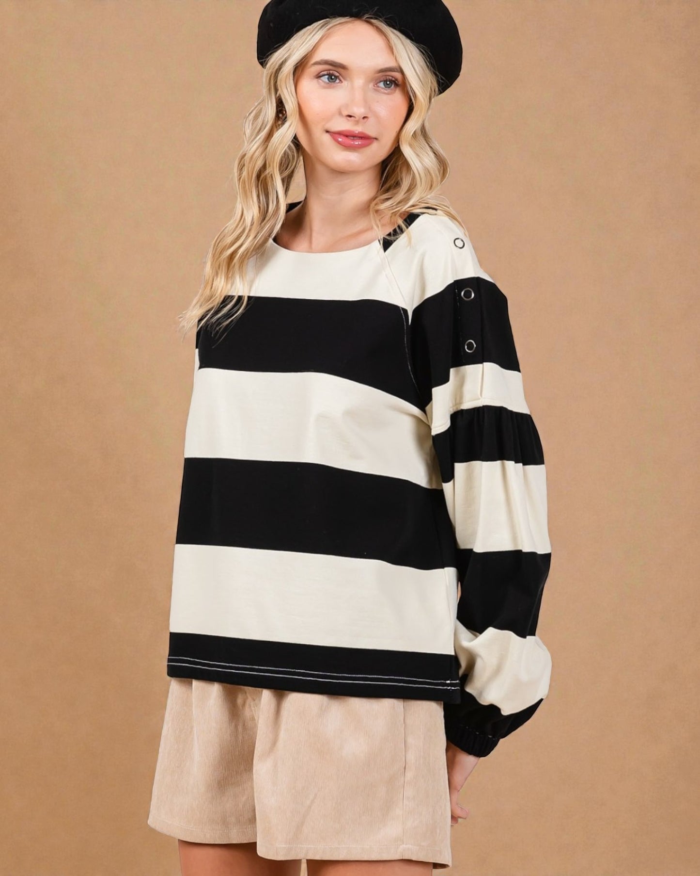 Woman wearing a black and white striped sweater with long sleeves on a beige background