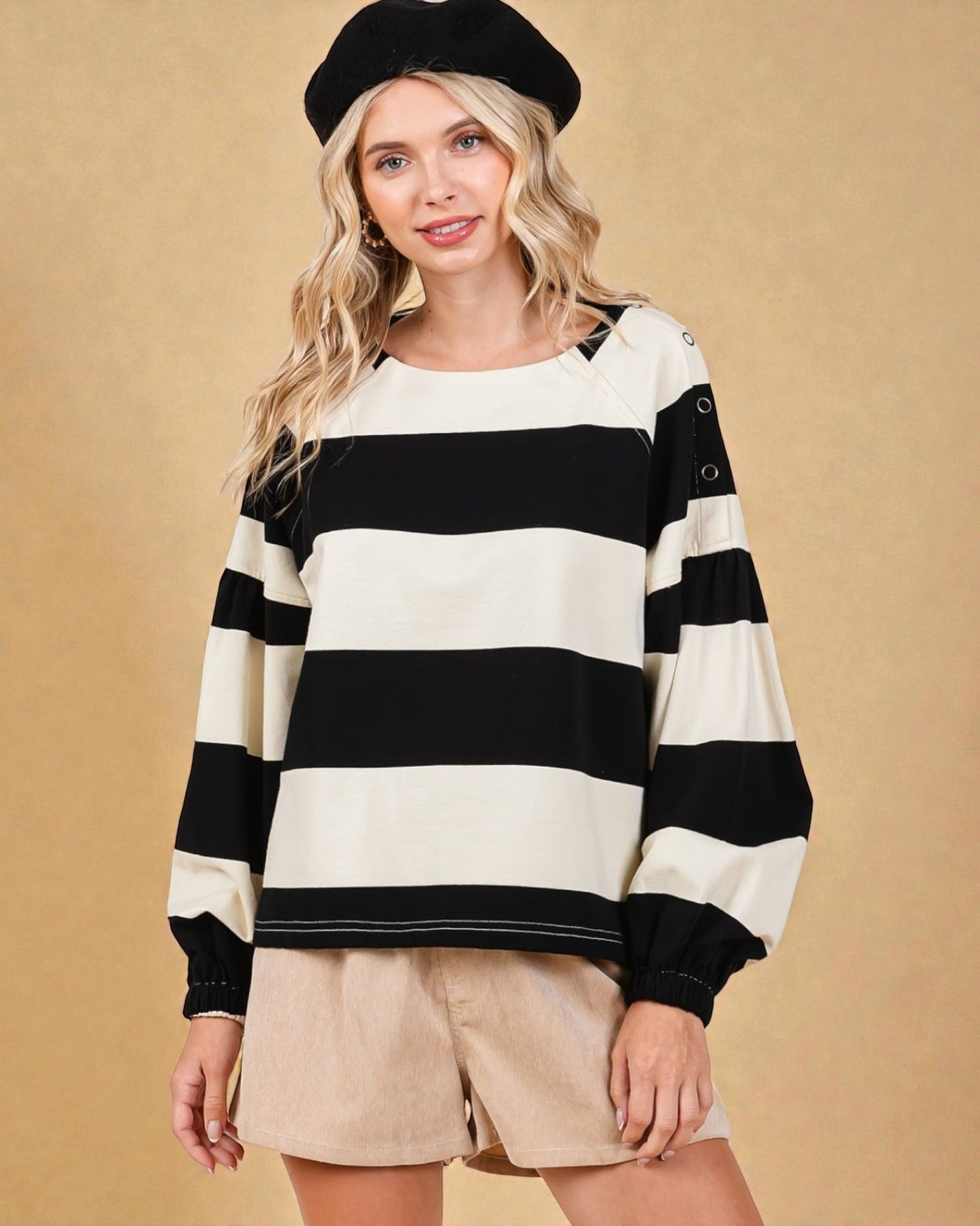 Woman wearing a black and white striped sweater with a beige background