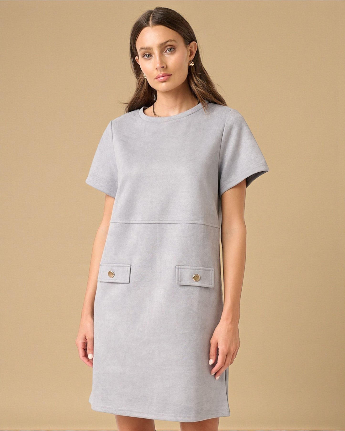 Woman wearing a gray dress with front pockets on a beige background