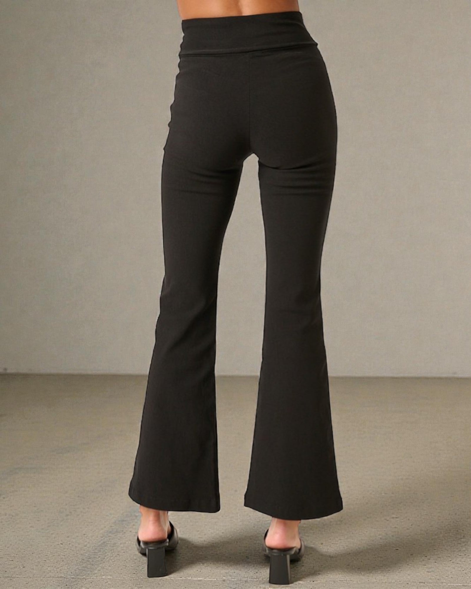 Black flared pants worn by a person on a neutral background