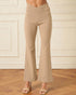 Beige flared pants worn by a person on a wooden floor with a white paneled wall background