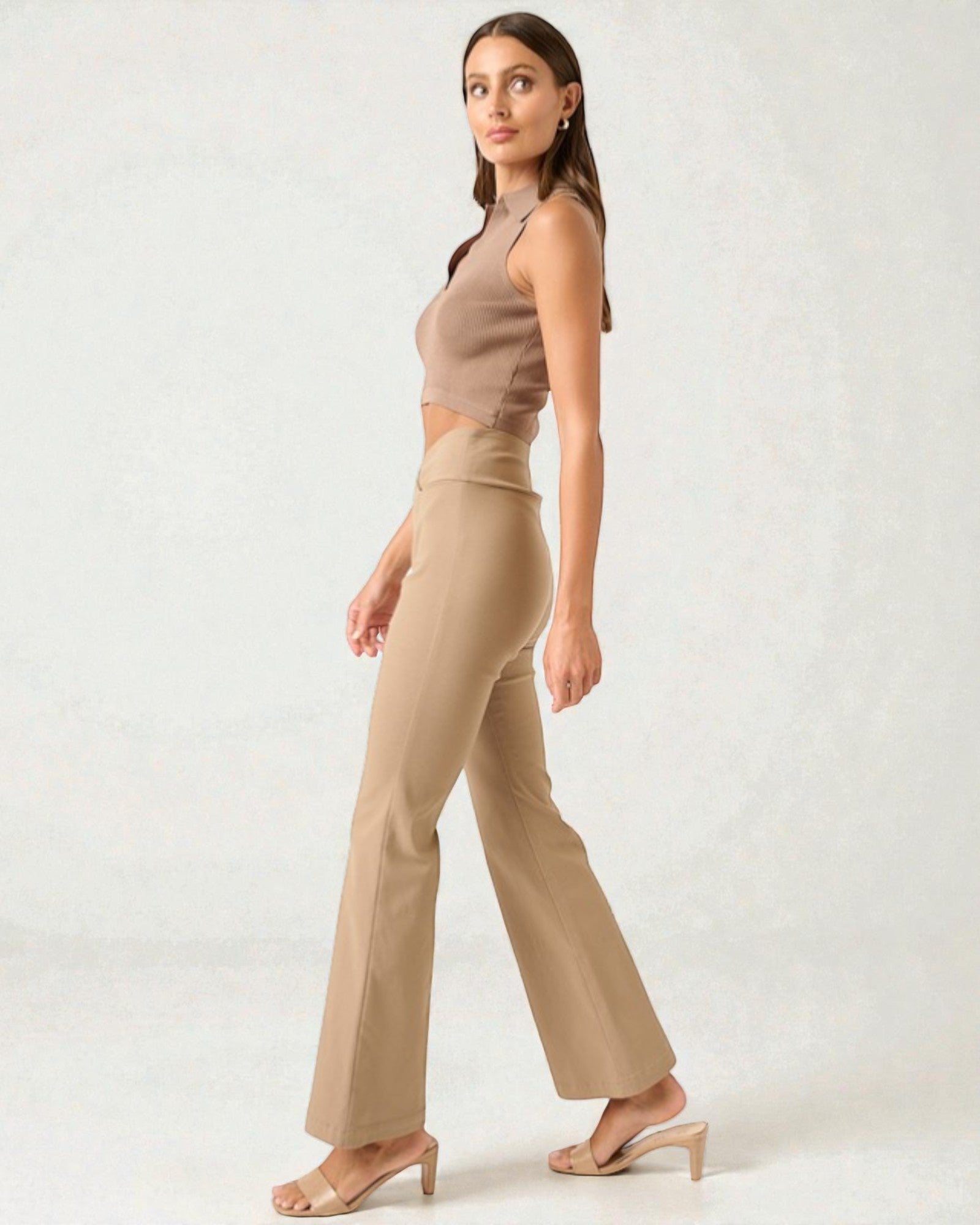 Woman wearing a beige sleeveless top and pants on a white background