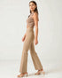 Woman wearing a beige sleeveless top and pants on a white background