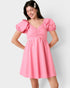 Woman wearing a pink dress with puffed sleeves on a white background