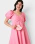 Woman wearing a pink dress holding a heart-shaped 'LOVE' sign against a white background