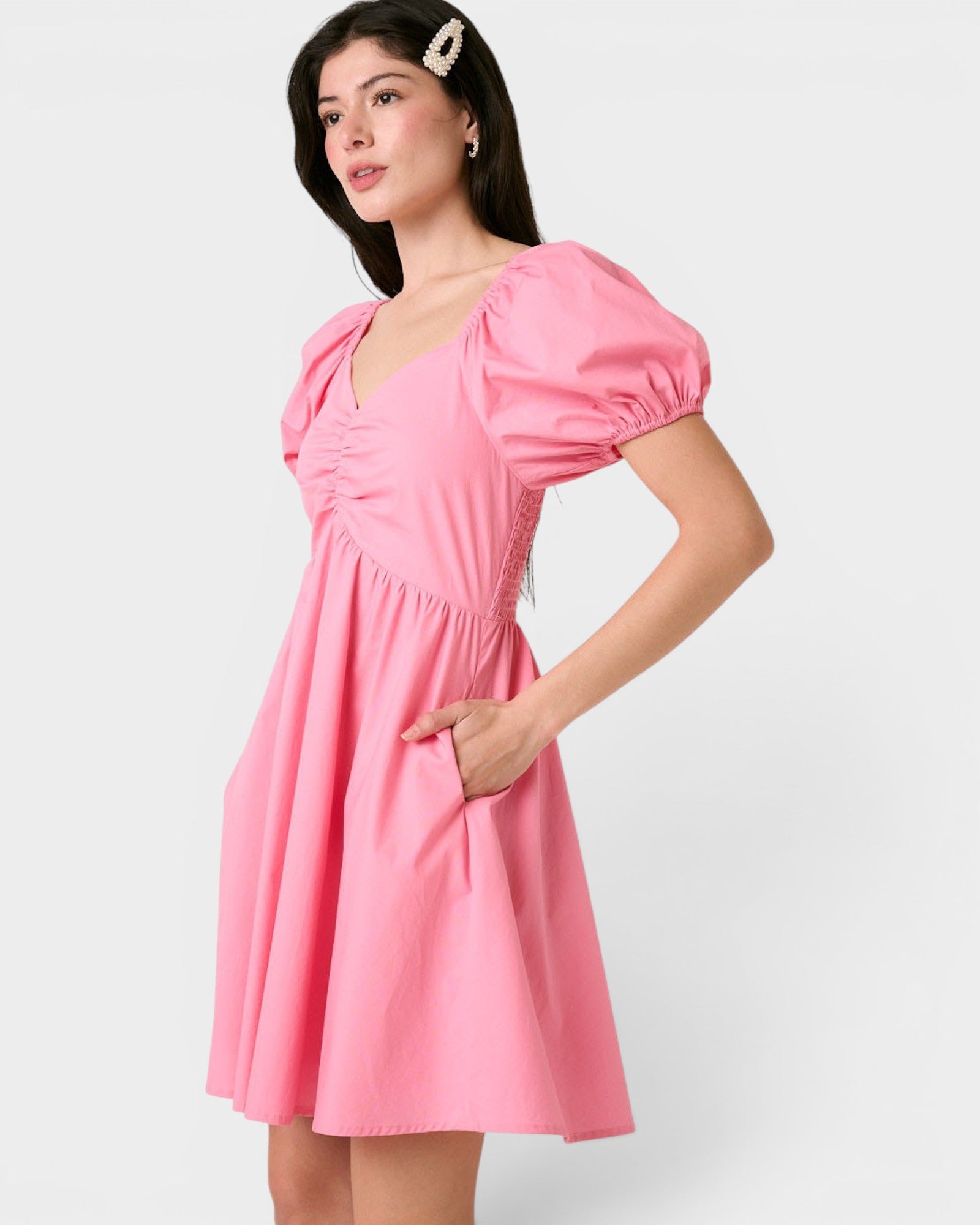 Woman wearing a pink dress with puff sleeves on a white background