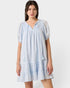 Woman wearing a light blue dress with smocked bodice and tiered skirt on a white background