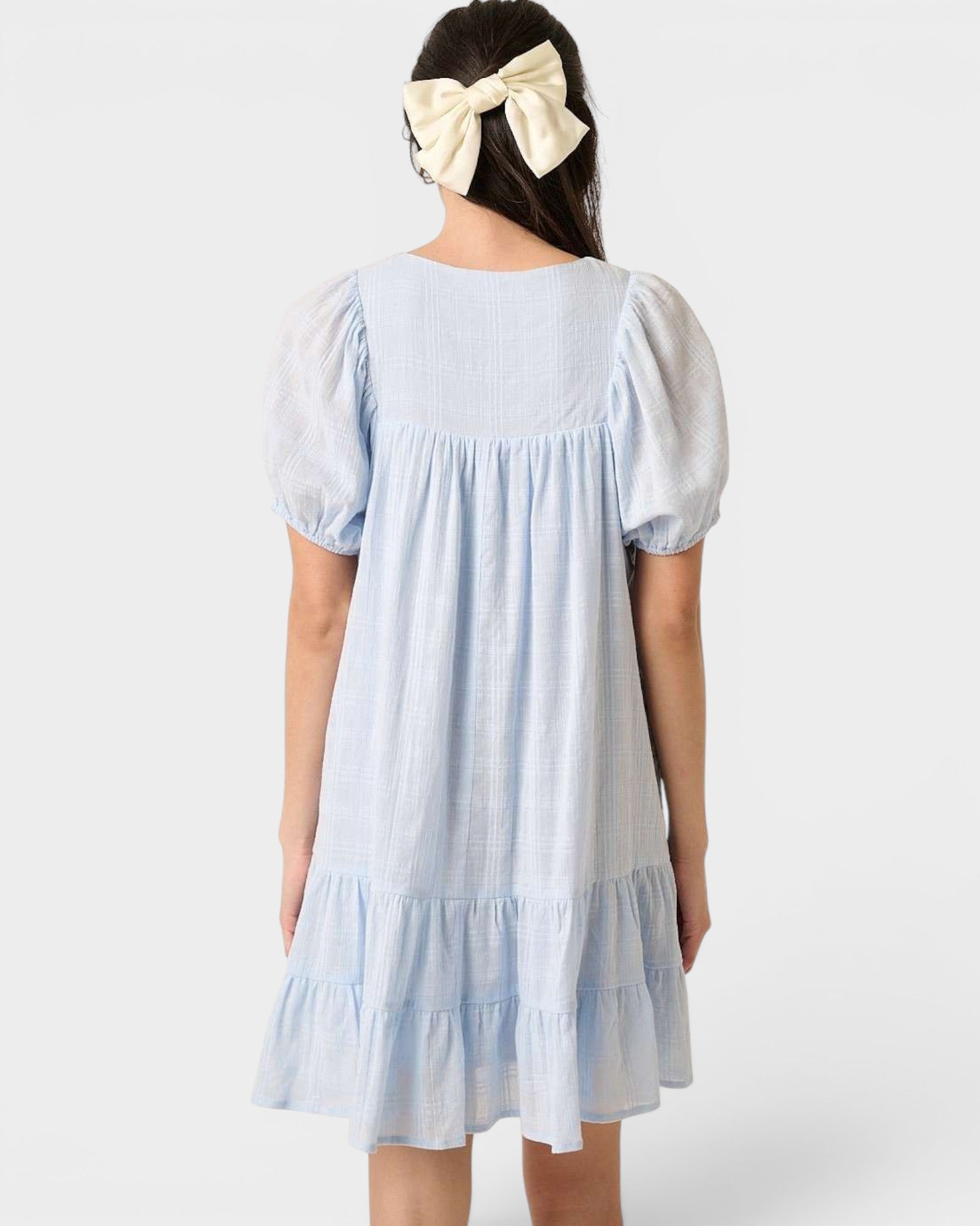 Light blue dress with puffed sleeves worn by a person on a white background