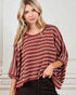 Woman wearing a red and white striped sweater against a white wall.