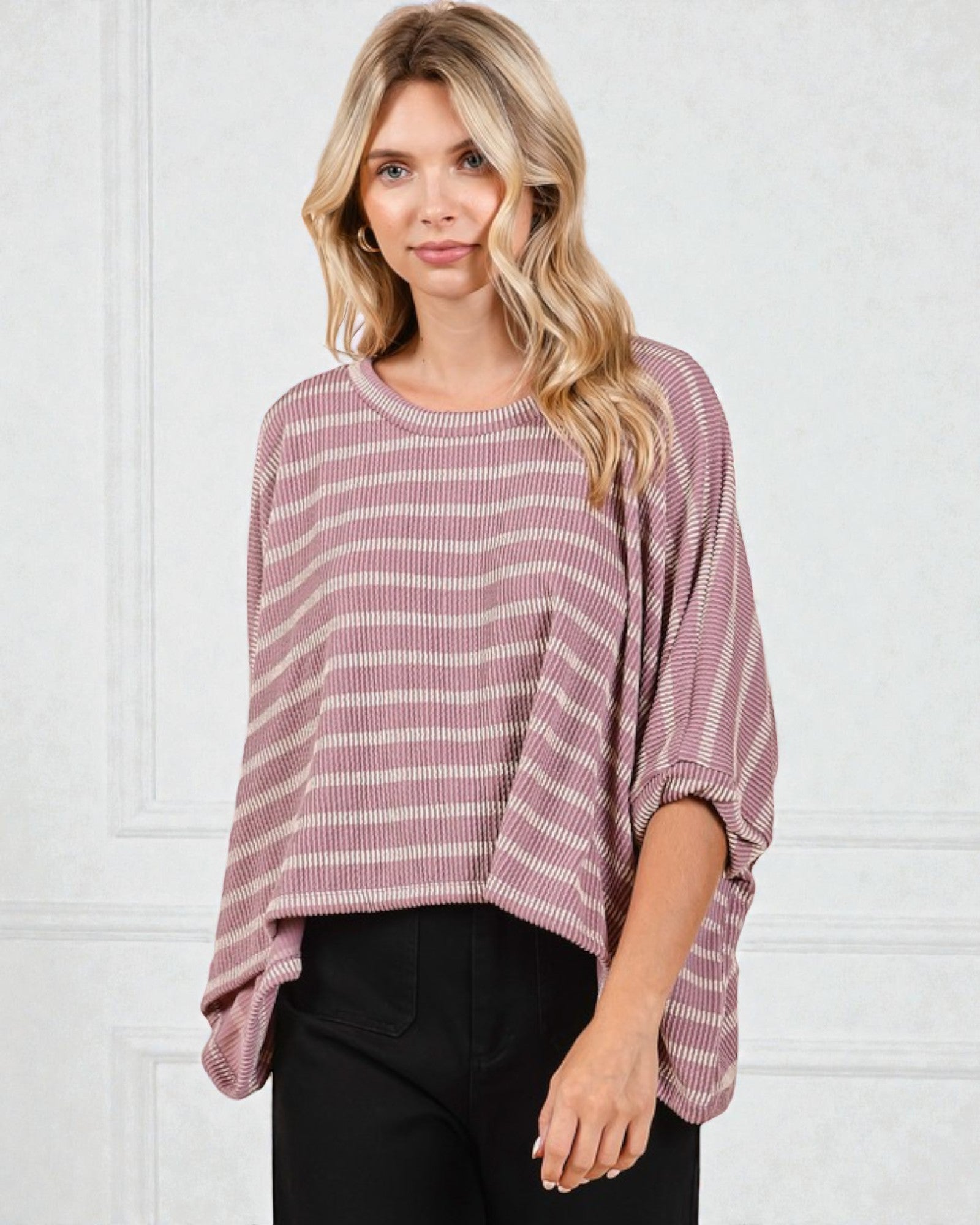 Woman wearing a pink and white striped sweater against a white background