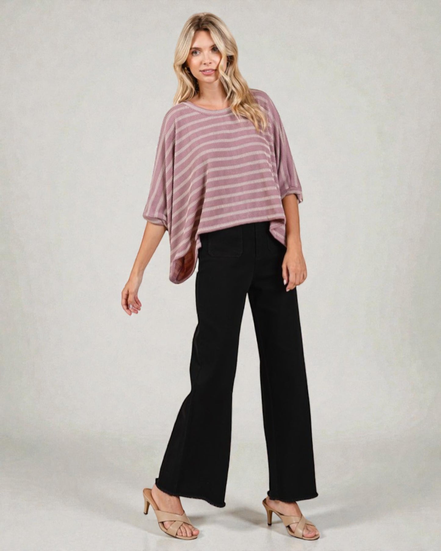 Woman wearing a striped top and black pants on a plain background