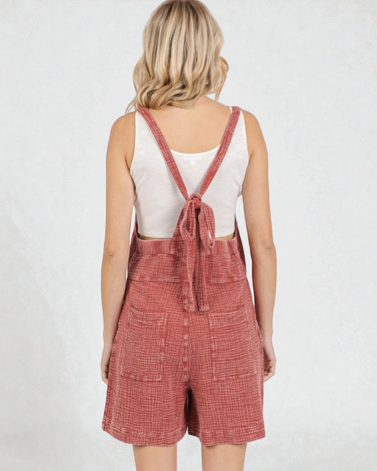 Person wearing red checkered overalls on a white background