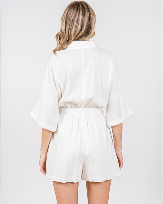 Person wearing a white romper on a plain background