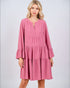 Woman wearing a pink dress with long sleeves on a light gray background