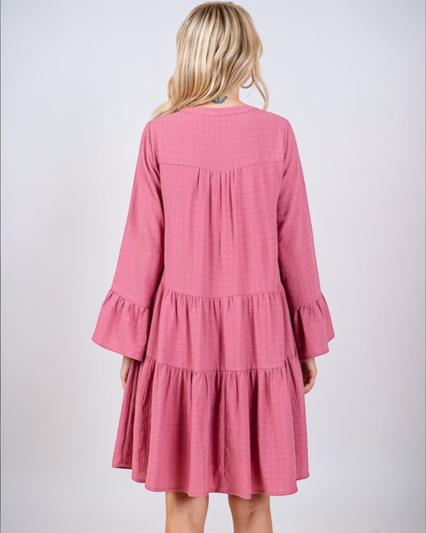Pink dress with ruffled sleeves and layers on a white background