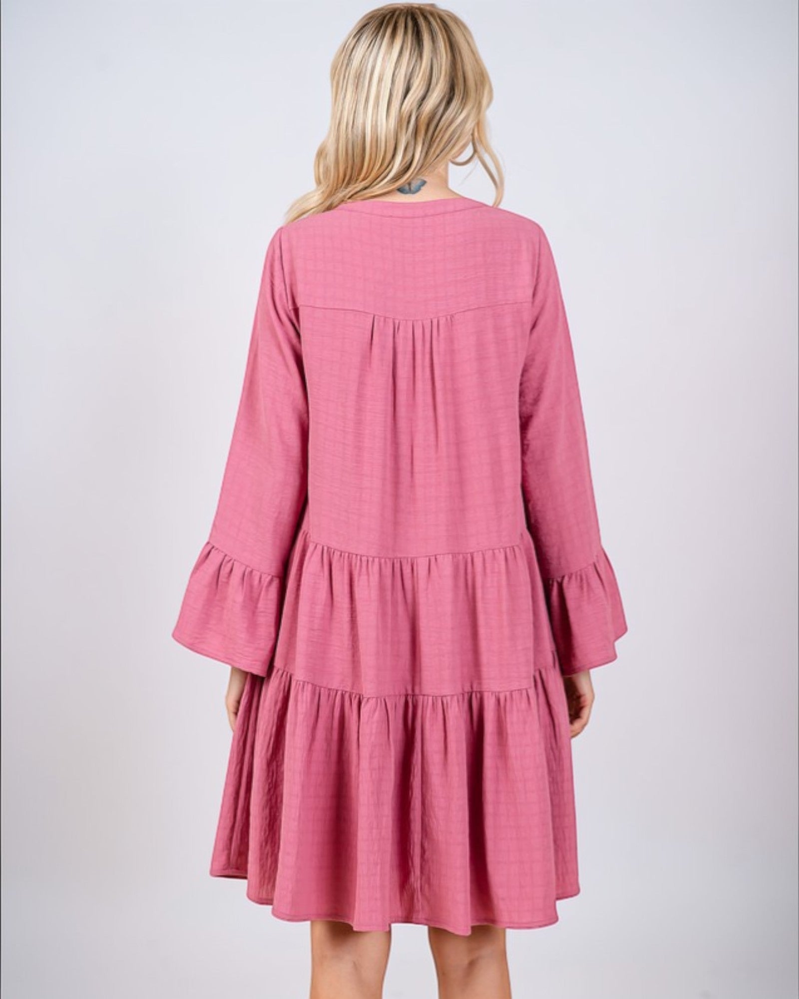 Pink dress with ruffled sleeves and layers on a white background