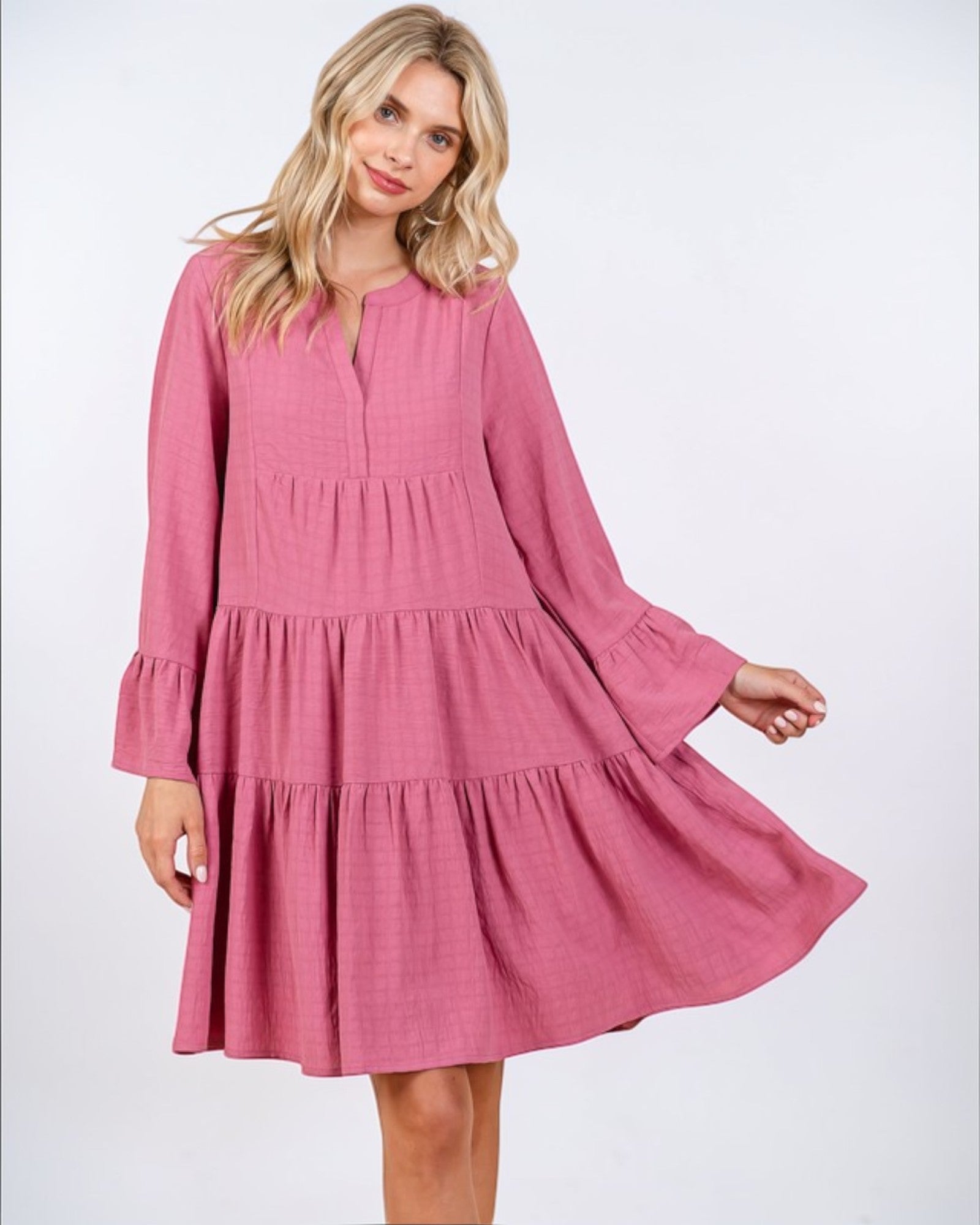 Woman wearing a pink dress with long sleeves on a white background