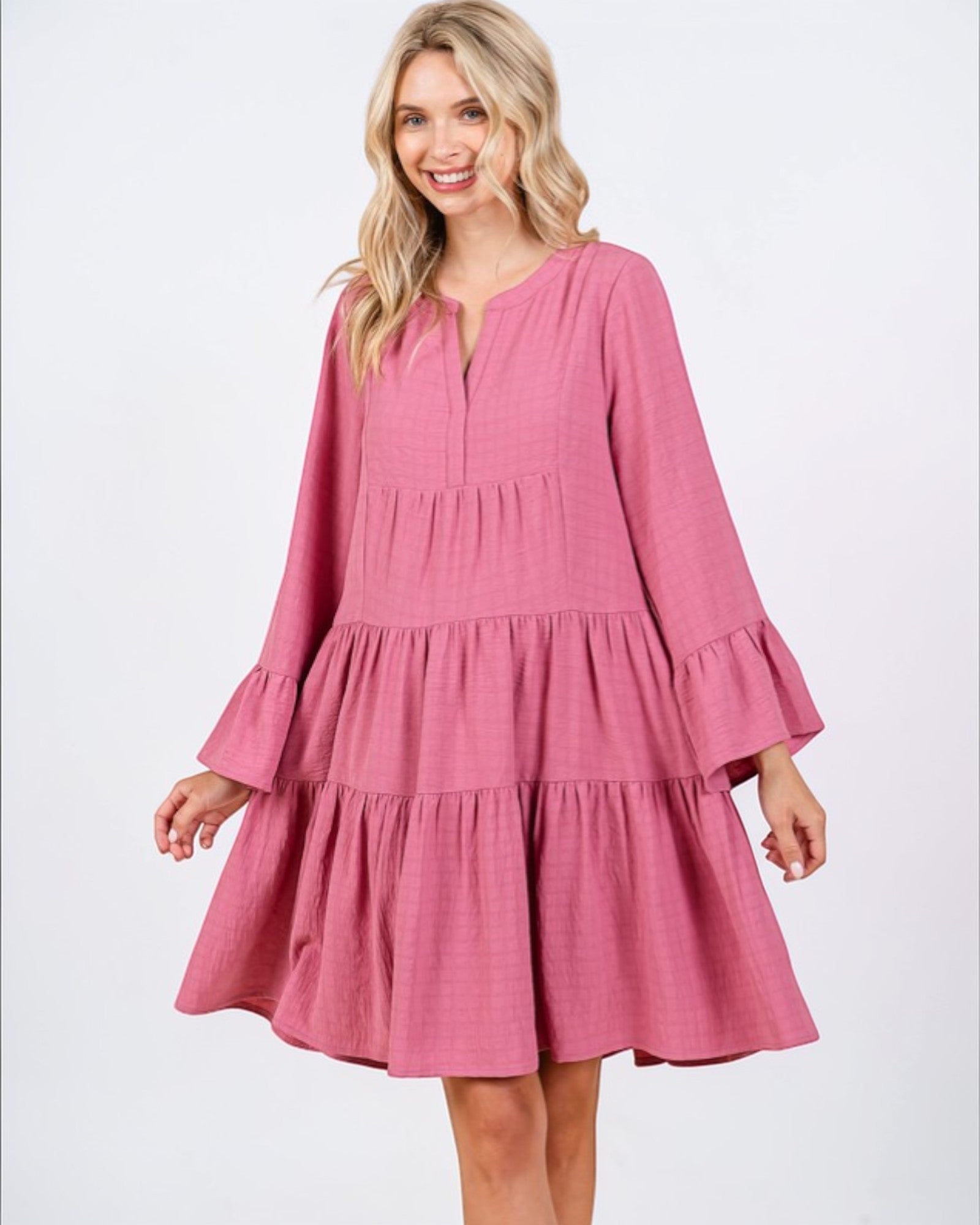 Woman wearing a pink dress with ruffled sleeves on a white background