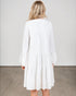 Woman wearing a white dress against a plain background