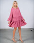 Woman wearing a pink dress with long sleeves on a plain background