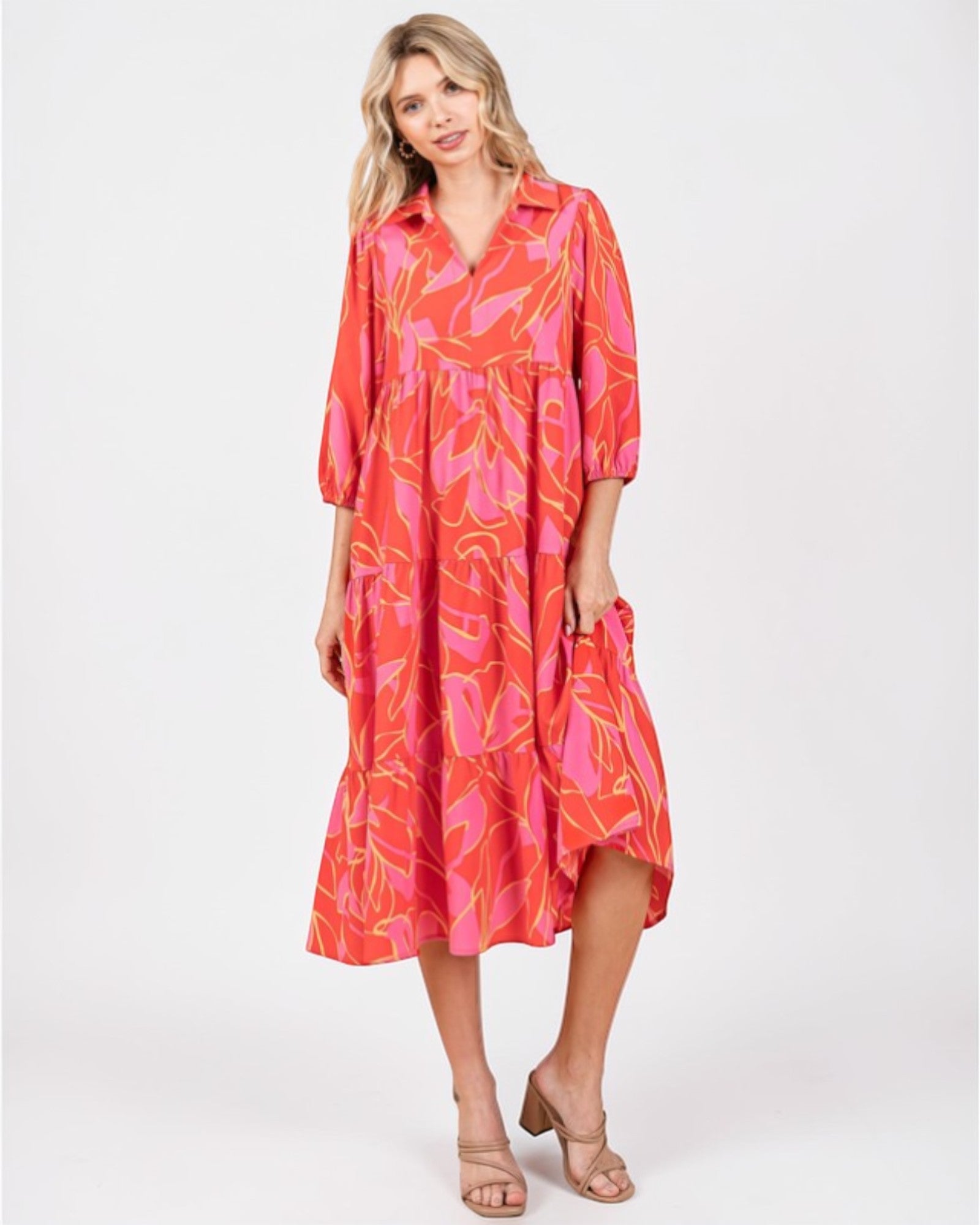 Woman wearing a vibrant pink and orange dress with floral pattern on a white background