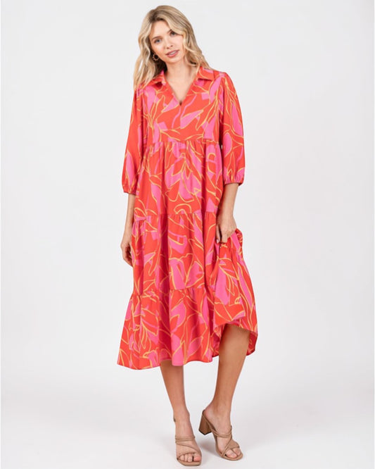 Woman wearing a vibrant pink and orange dress with floral pattern on a white background