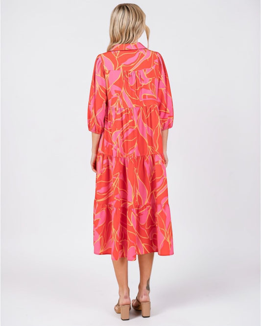 Woman wearing a vibrant orange and pink dress with abstract pattern on a white background