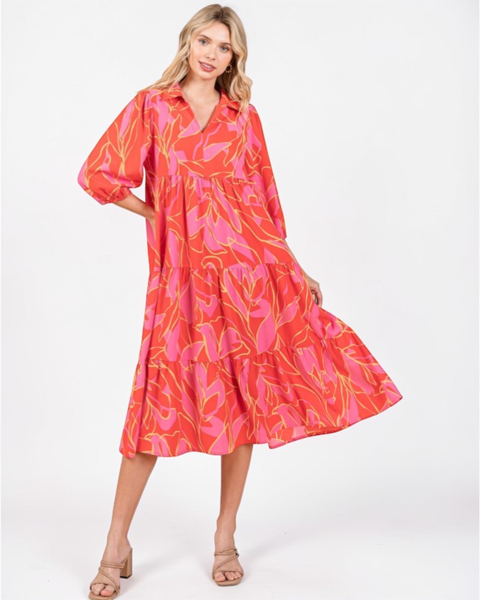 Woman wearing a vibrant pink and orange dress with a floral pattern on a white background