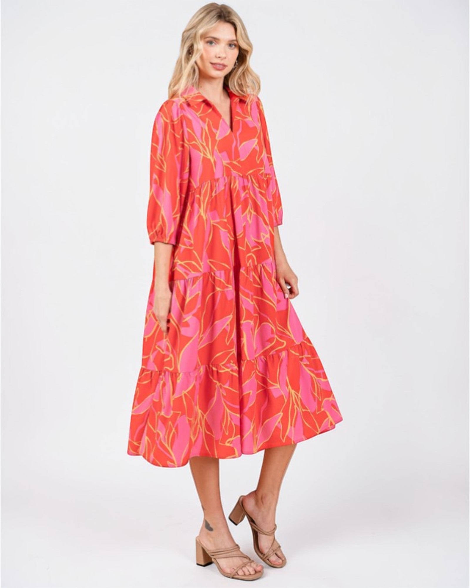 Woman wearing a vibrant pink and orange dress with leaf patterns on a white background