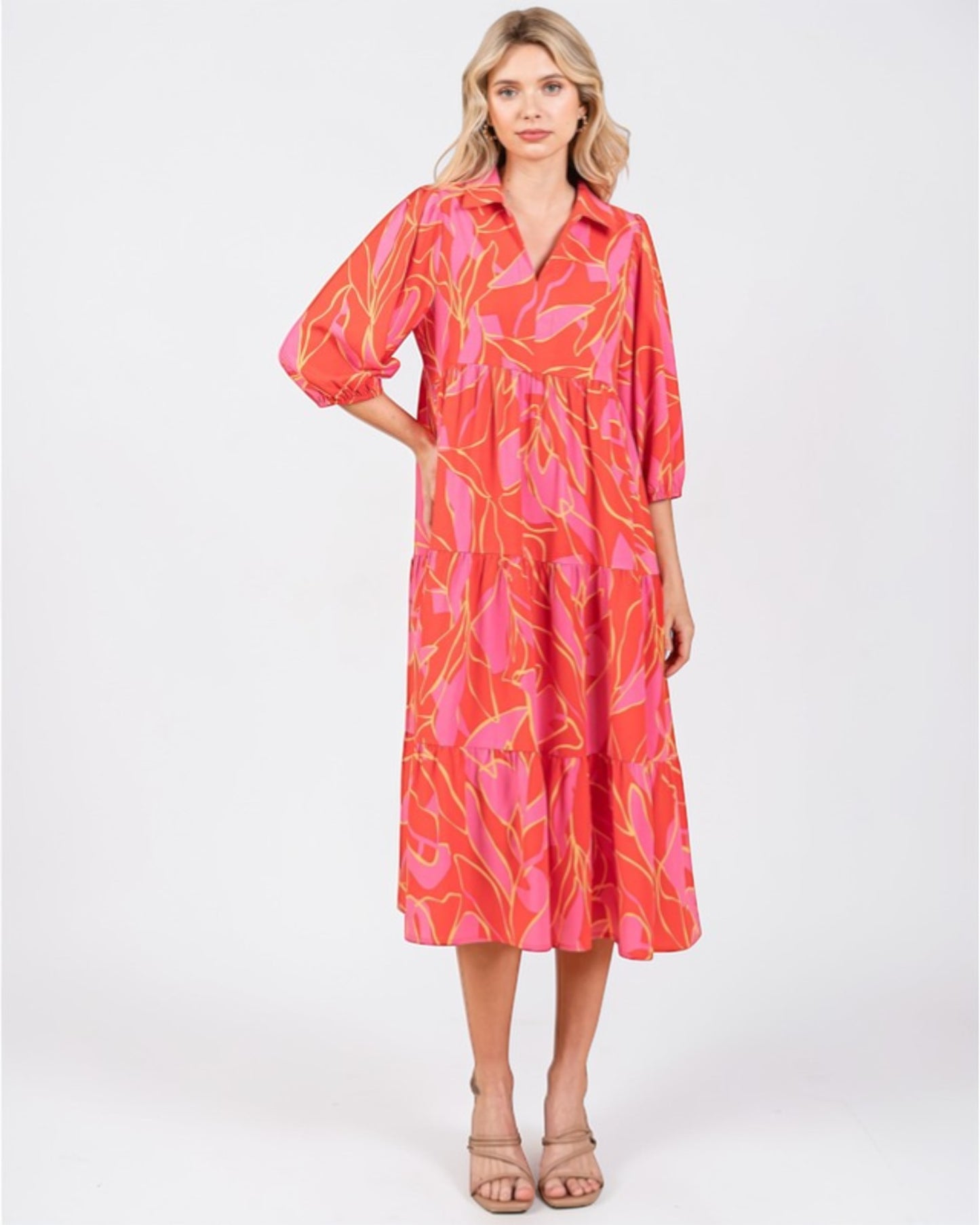 Woman wearing a vibrant pink and orange patterned dress on a white background