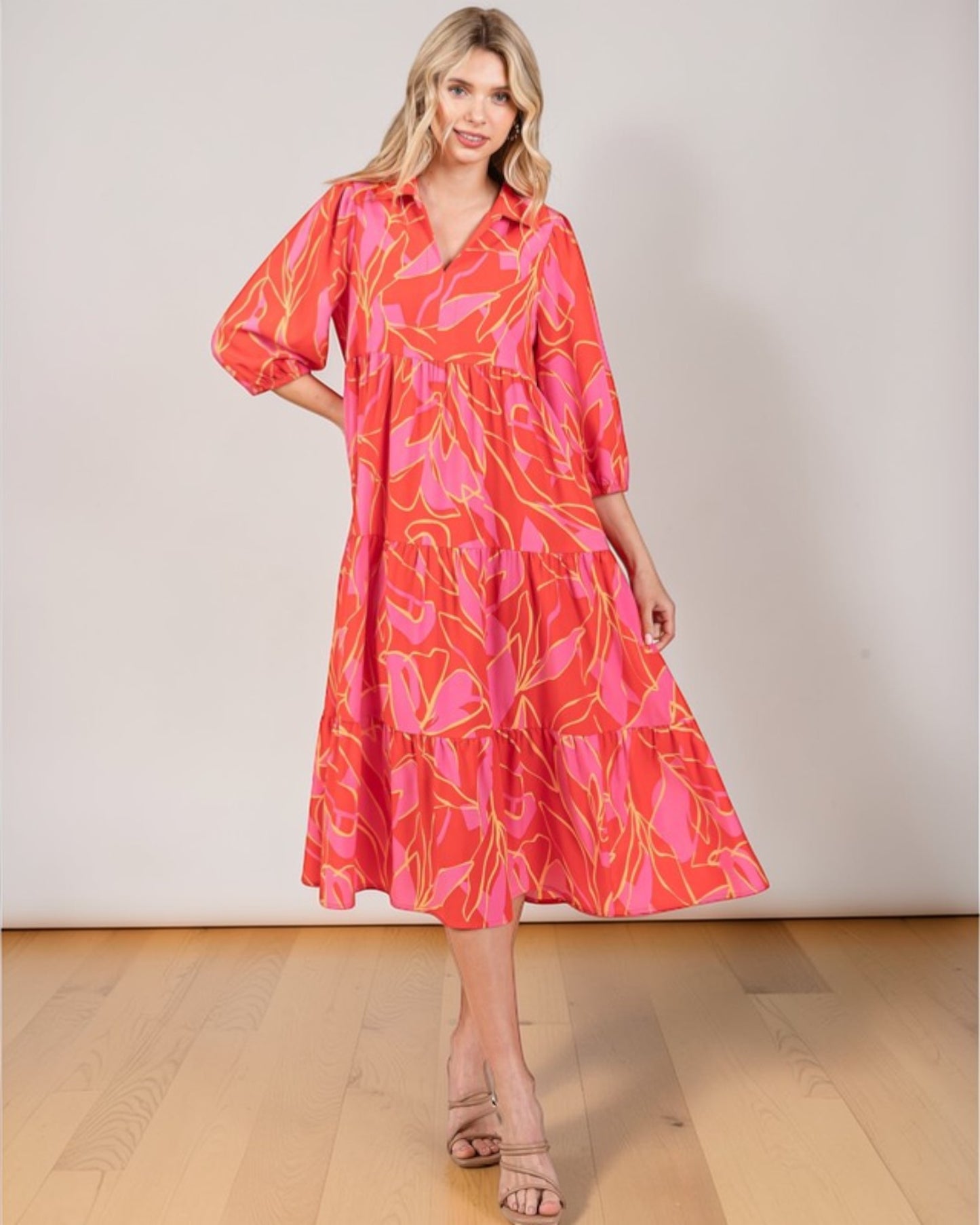 Woman wearing a red and pink patterned dress on a plain background