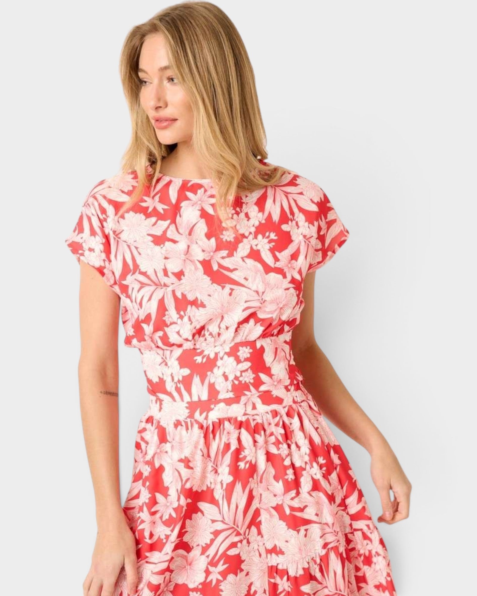 Woman wearing a red floral dress against a white background