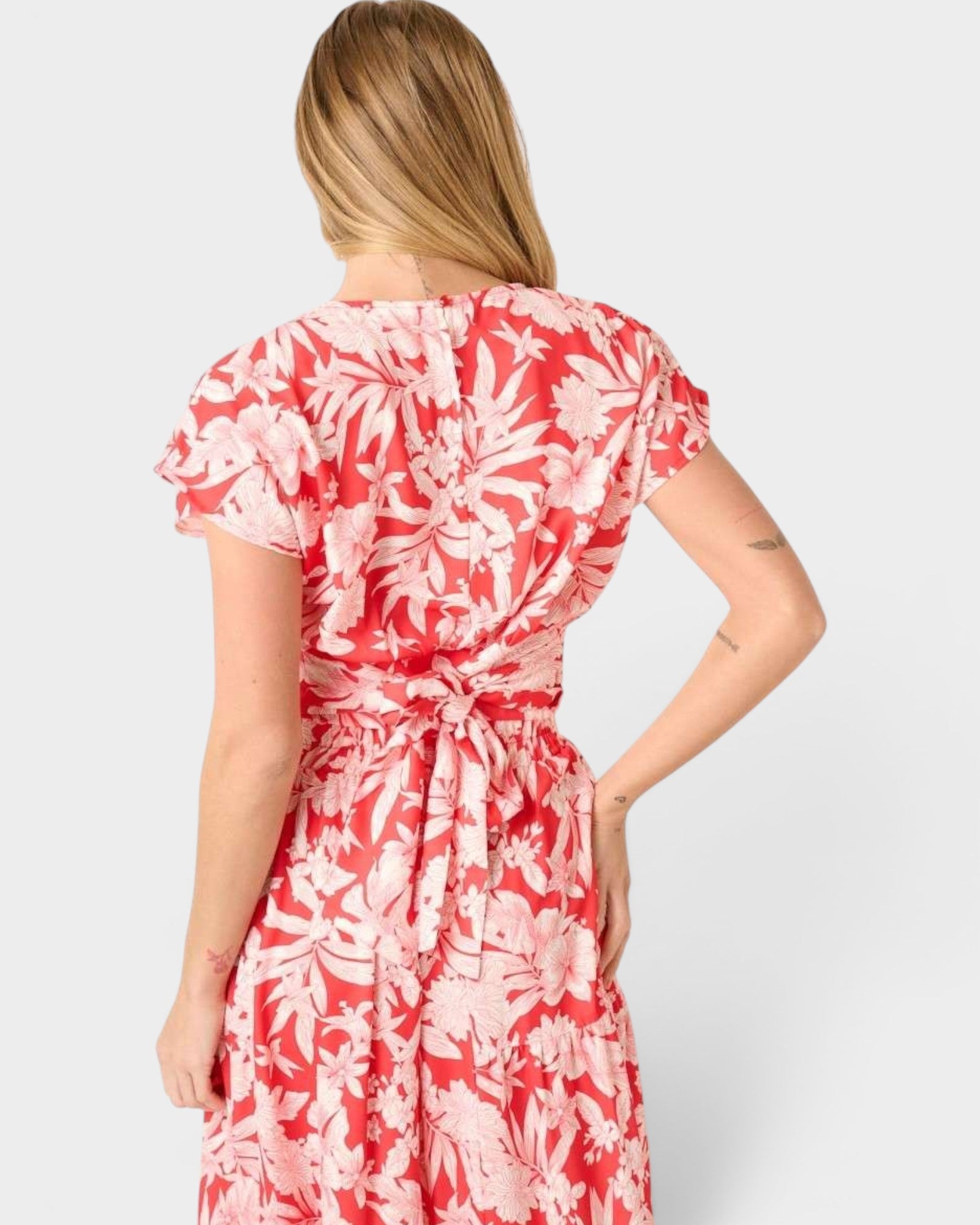 Woman wearing a red and white floral dress on a plain background