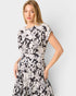 Woman wearing a black and white floral dress against a plain background