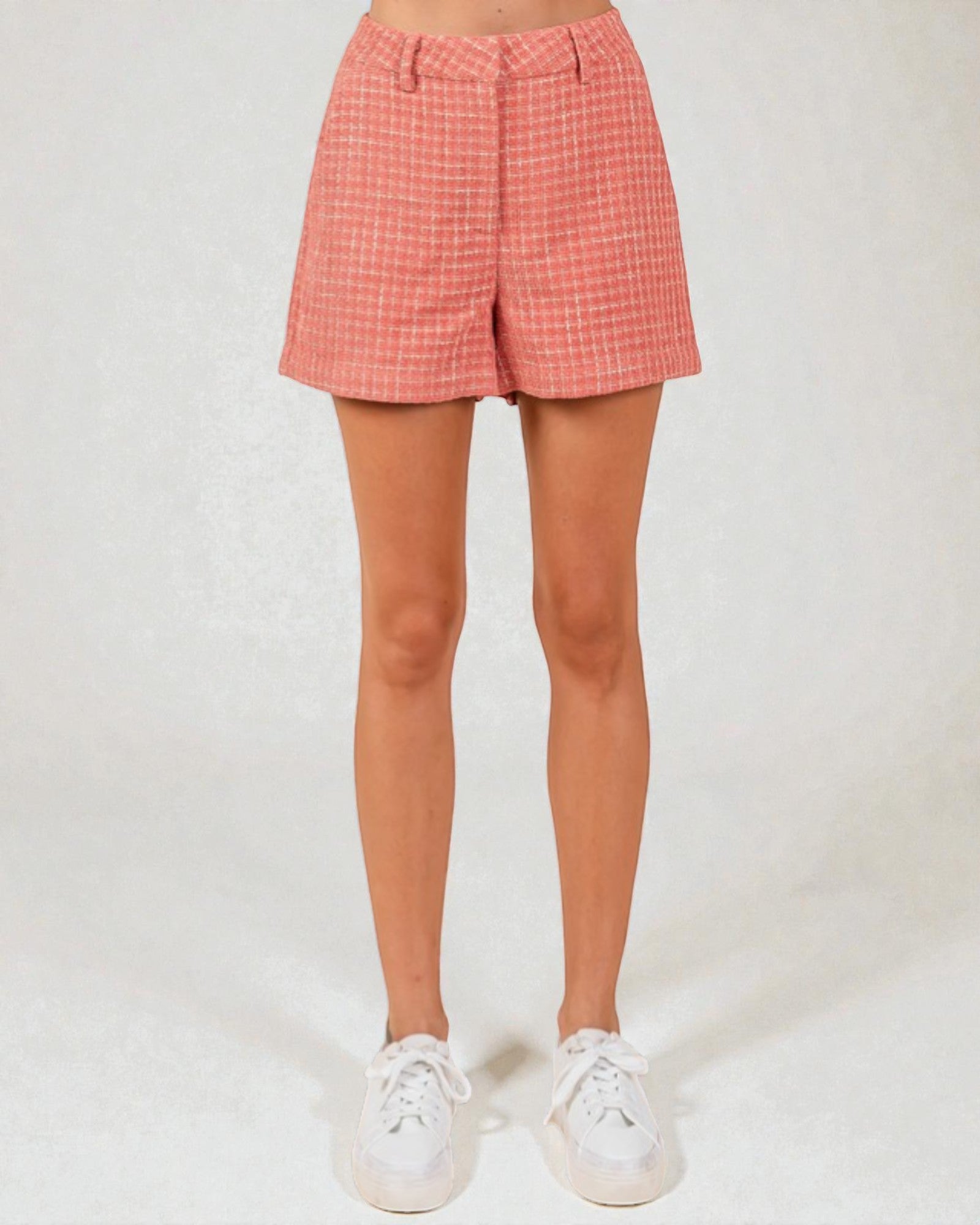 Person wearing pink plaid shorts on a white background