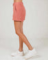 Person wearing a pink checkered skirt and white sneakers on a light gray background