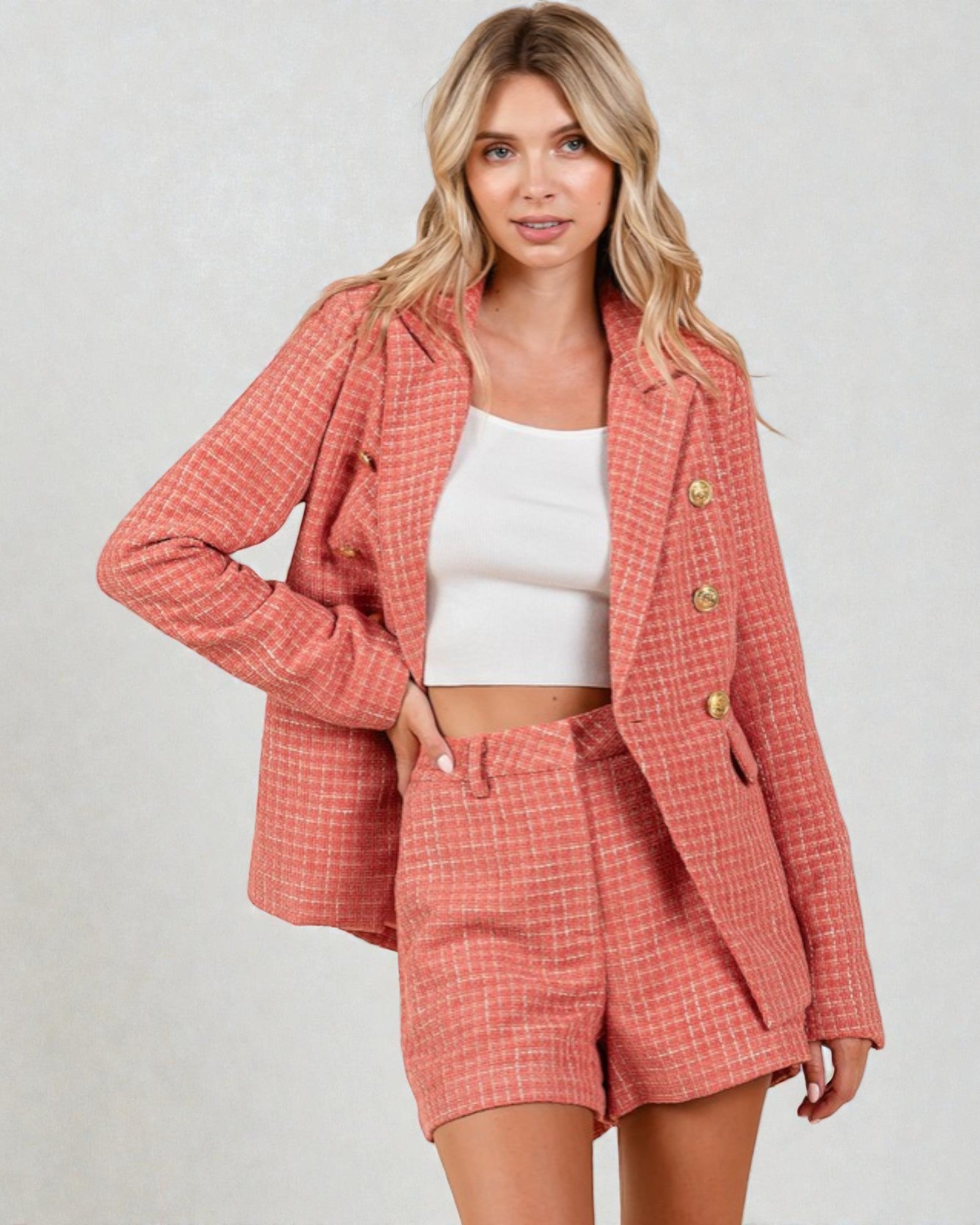 Woman wearing a coral plaid outfit with a matching jacket and shorts on a plain background