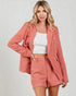 Woman wearing a coral plaid outfit with a matching jacket and shorts on a plain background