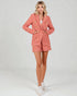 Woman wearing a coral checkered suit with white sneakers on a light gray background
