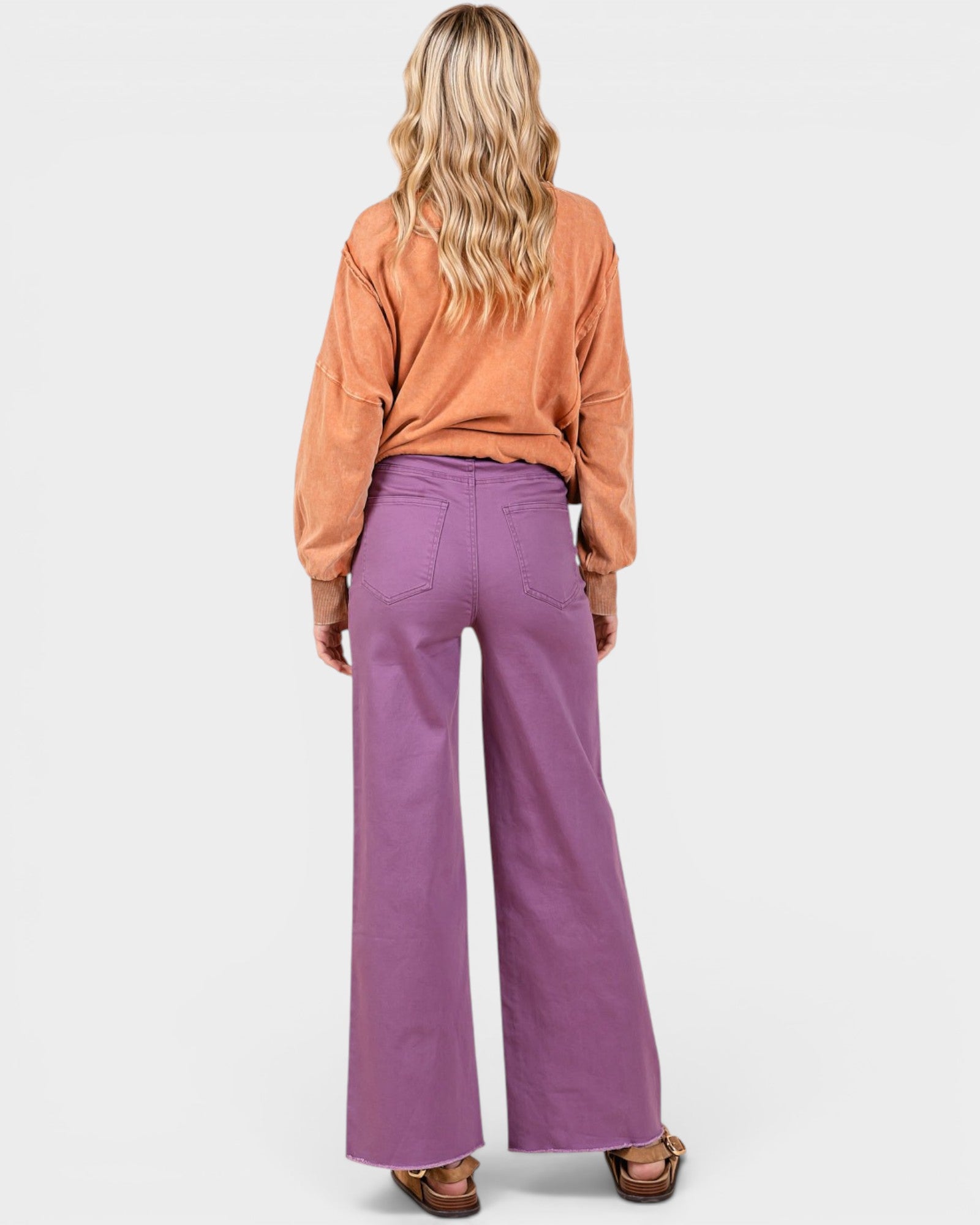 Person wearing a brown shirt and purple pants on a white background