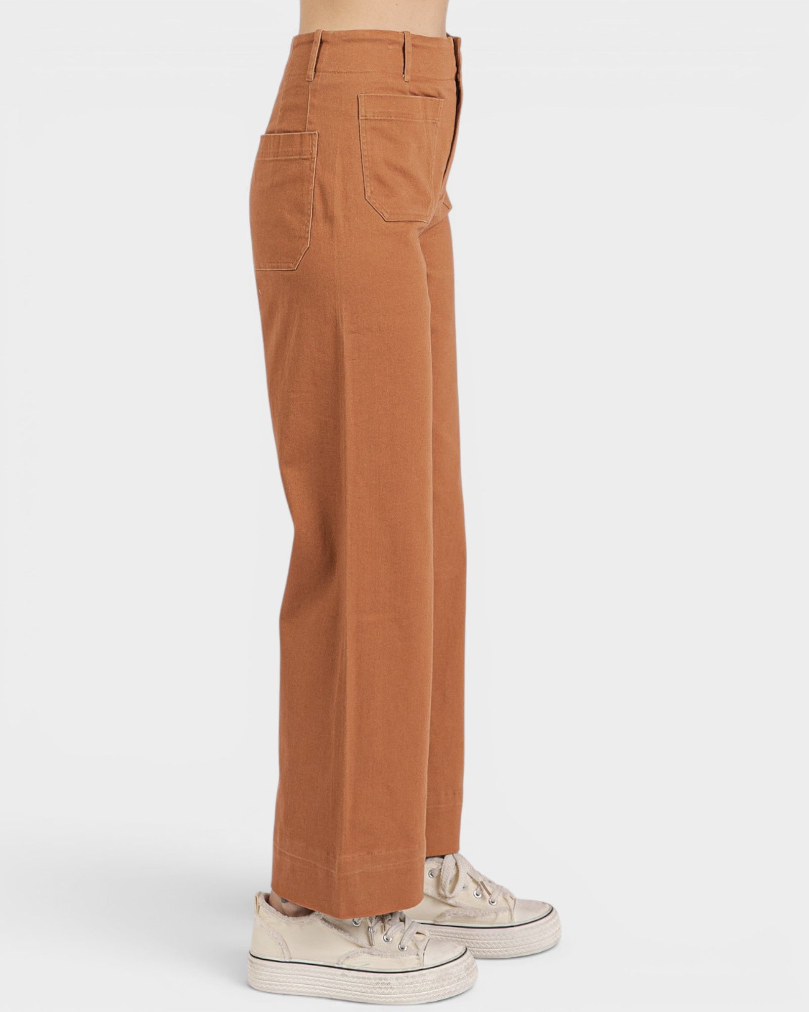 Brown pants worn by a person on a white background