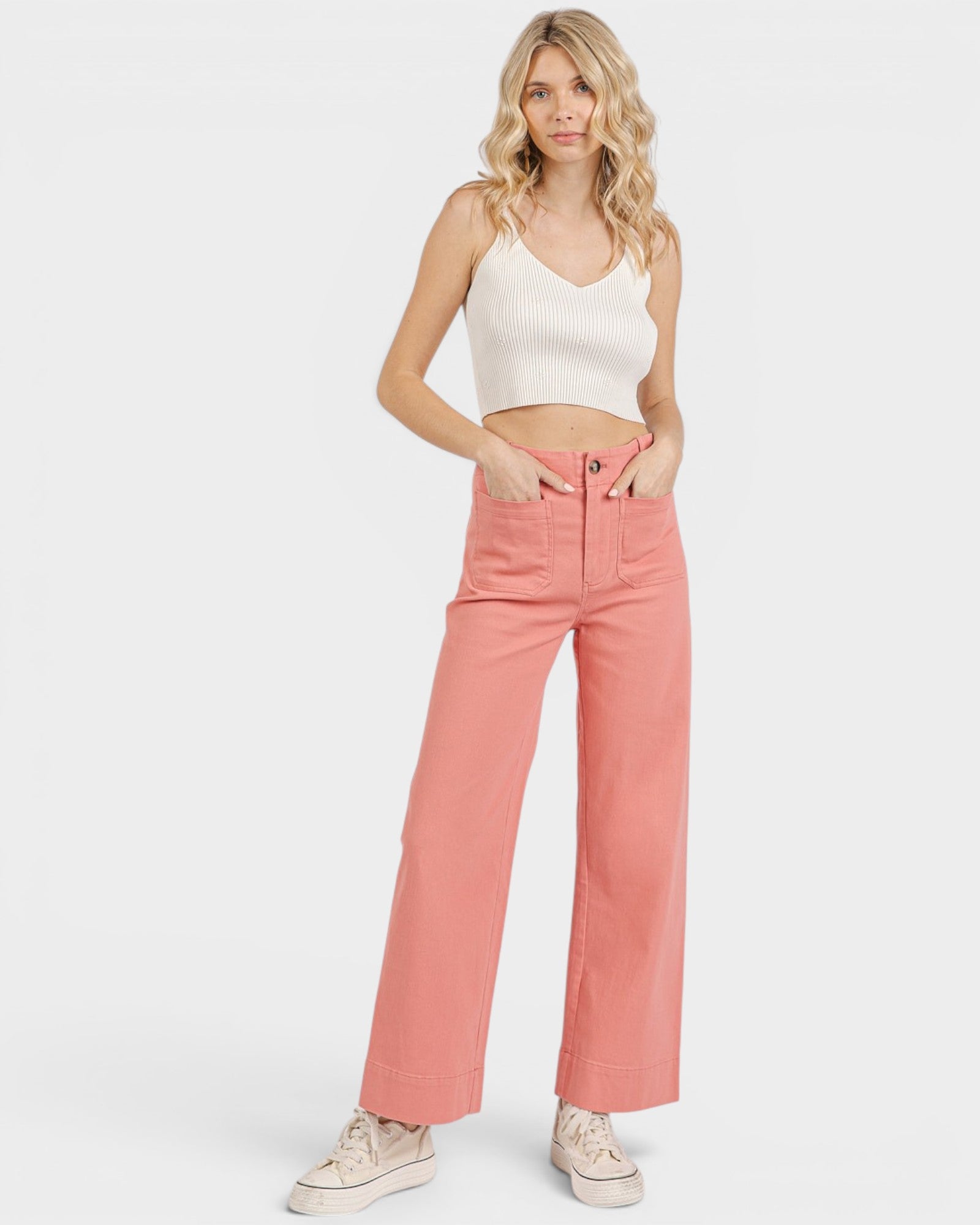 Woman wearing a white top and pink pants on a white background